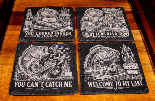 Four BassZilla fishing humor slate coaster designs arranged on a wooden tray